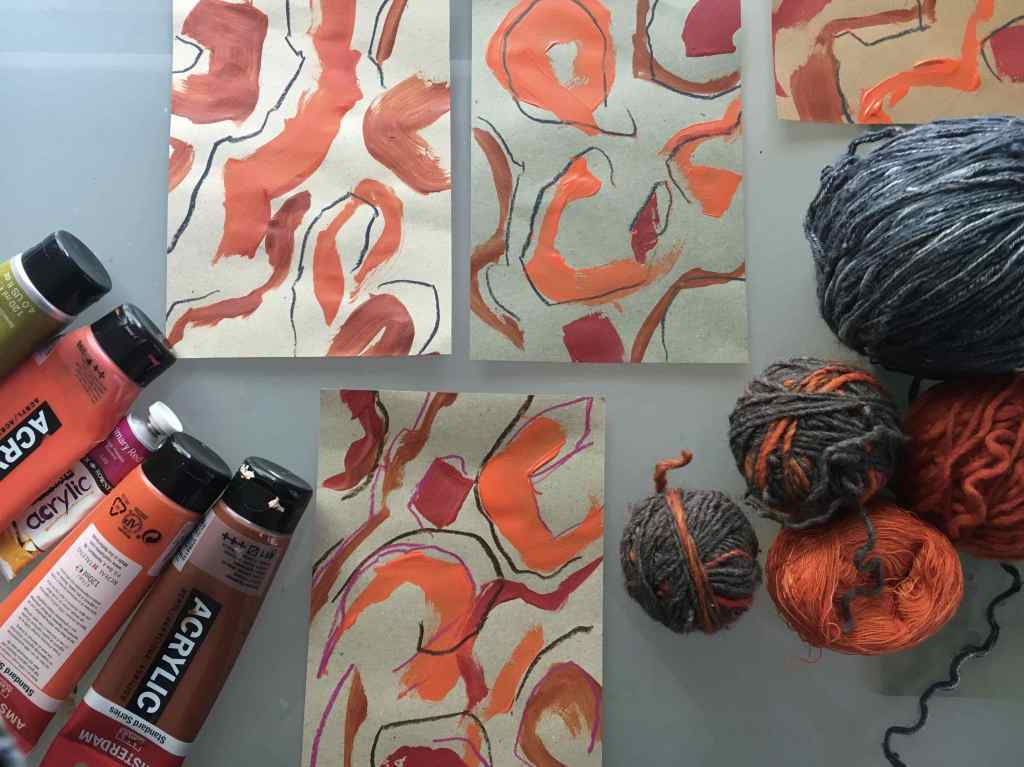 Orange and blue grey balls of yarn with acrylic paint and abstrct sketches